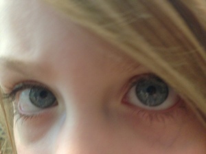 Close up photo showing only the bright blue eyes eyes of young child. Blonde hair falls over part of the left eye.